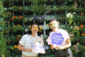 Guest posing at a photo booth rental in Vancouver with floral photo booth backdrop and custom photo booth props for Mother’s Day.