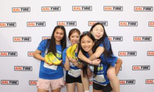 Group of runners posing with bananas in front of a Kal Tire photo booth backdrop at Vancouver Sun Run, captured in fun photo booth photos.