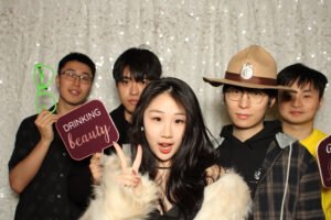 Group of friends posing with fun photo booth props in front of a sparkly photo booth backdrop at a Vancity Photo Booth experience.
