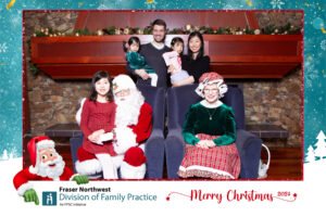 Family poses with Santa and Mrs. Claus in front of a festive photo booth backdrop at a Vancity Photo Booth rental holiday event.