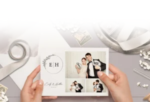 Holding a wedding card with photo booth images of a smiling bride and groom posing with Mr. and Mrs. signs